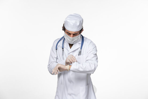 消毒正面图男医生穿着医用西服 戴着无菌口罩作为防护罩 看着自己手腕上的白壁病毒冠状病毒大流行疾病青年工人专家