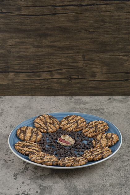 美味蓝色的饼干盘 巧克力和花生滴在大理石背景上美食花生坚果