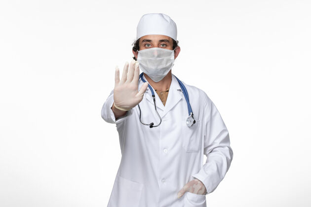 外套正面图身穿医疗服的男医生戴着口罩 以防柯维德-白墙病毒疾病柯维德-大流行穿着口罩男性