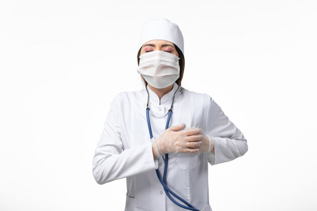 男人前视图女医生穿着白色医疗服 戴着口罩 由于白墙上大流行疾病 医学病毒大流行 covid-病毒实验室外套女性
