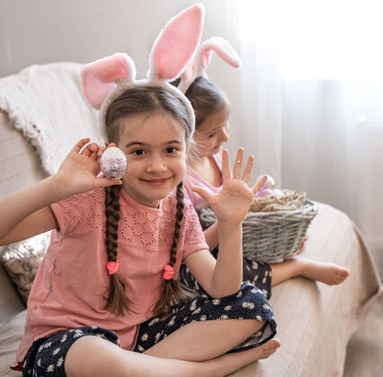 复活节带着兔子耳朵的小姐妹们拿着复活节彩蛋在镜头前摆姿势准备鸡蛋童年