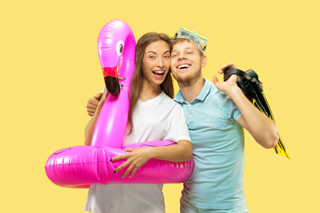 哇美丽的年轻夫妇的半身像在黄色空间女人和男人站在粉红色的游泳圈作为火烈鸟和脚蹼浪漫派对迪斯科