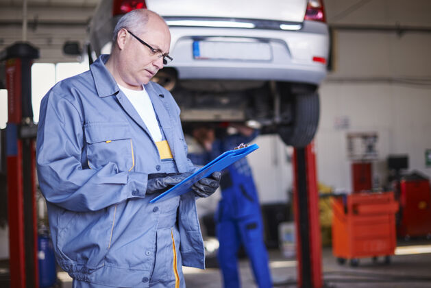 汽车修理厂修理工在车间里修理汽车成人忙碌工业