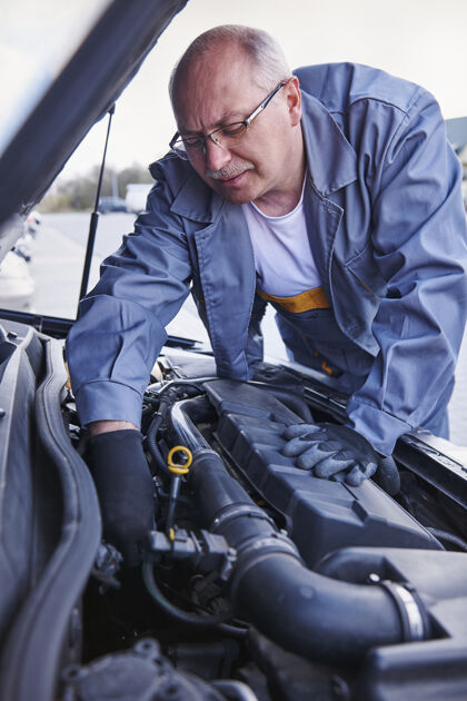 成年男子机修工正在检查一辆车防护服眼镜检查