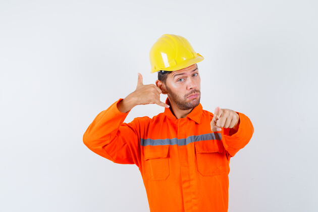 起重机建筑工人穿着制服 戴着头盔指着电话牌 看上去很自信正视图工程人员设备