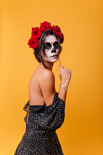 女人身材苗条的黑发女孩 穿着连衣裙摆出美丽的姿势 露肩神秘的墨西哥女人带着僵尸面具的肖像死亡服装幽灵