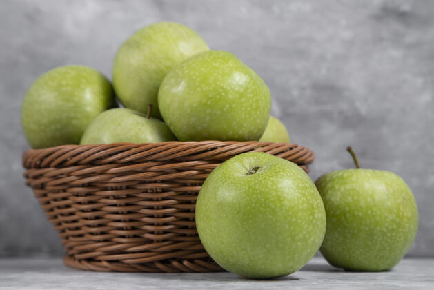有机一篮柳条装的新鲜青苹果放在石头上成熟植物苹果