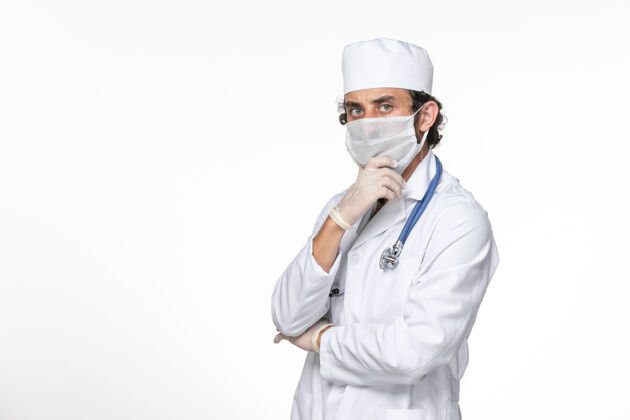 防护正面图：男医生穿着医疗服 戴着无菌口罩 以防被冠状病毒感染摆姿势思考白墙飞溅病毒冠状病毒大流行的健康问题病毒冠状病毒思考