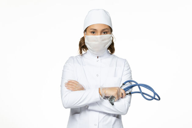 穿戴正面图女医生身穿白色医疗服戴口罩因冠状病毒在白墙上大流行病毒隔离疾病大流行护士