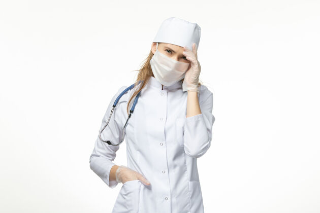 疾病正面图女医生穿着医疗服 带着无菌口罩 因白墙上冠状病毒病大流行健康冠状病毒套装护士冠状病毒预防