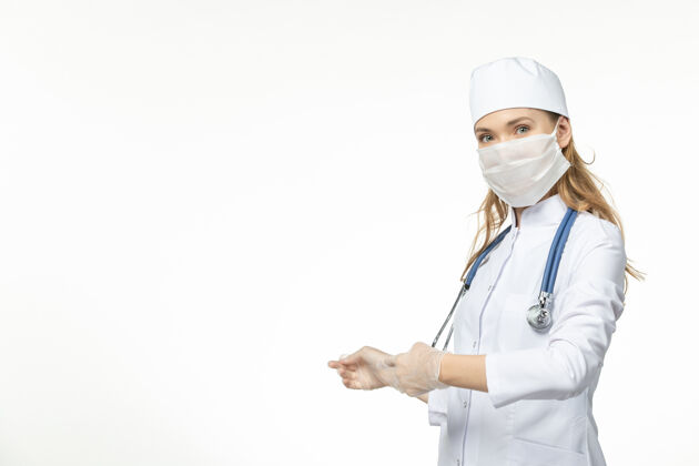 病毒正面图：女医生穿着医疗服 戴着口罩和手套 因为在浅白的办公桌上有冠状病毒疾病大流行健康冠状病毒护士药品女性