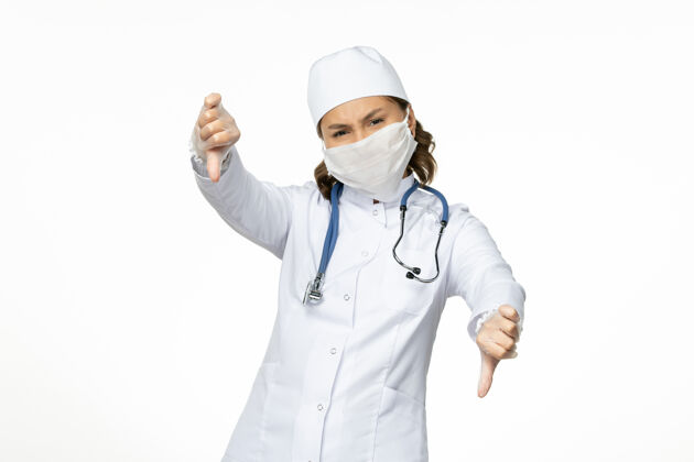 疾病正面图女医生穿着白色医疗服 戴着口罩 由于白色办公桌上有冠状病毒大流行病毒疾病隔离冠状病毒前台医生到期