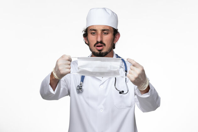病毒正面图：男医生穿着医疗服 戴着口罩 以防白色办公桌上的冠状病毒疾病-健康冠状病毒-大流行人员工作持有