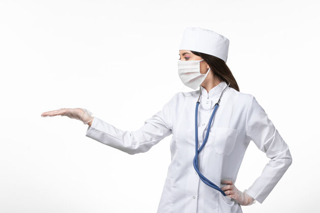 医学前视图女医生穿着白色医疗服 戴着口罩 因大流行于浅白墙上 医学大流行病毒covid-病毒女性人