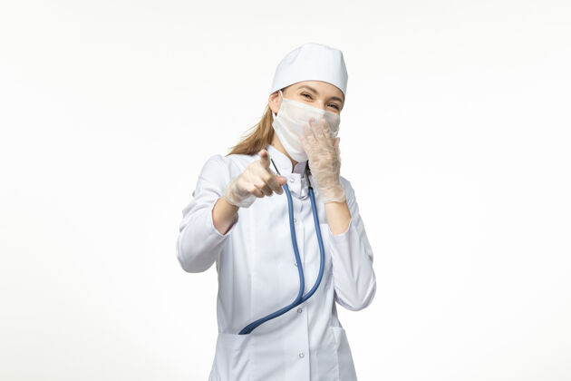 冠状病毒正面图：穿着白色医疗服 戴着口罩的女医生 可以抵御冠状病毒在白墙上笑的疾病——冠状病毒大流行肖像视野人
