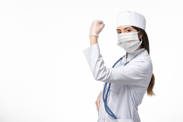 微笑正面图女医生穿着白色医疗服 戴着口罩 因冠状病毒在白墙上弯曲健康疾病大流行女性人疾病