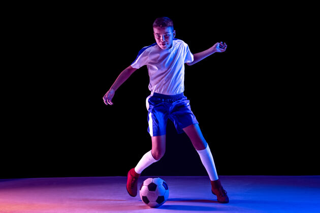 跑步小男孩像个足球运动员一样站在黑暗的墙上活动动态黑暗