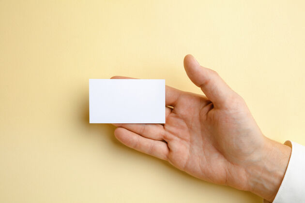 手臂男性手拿一张空白名片放在柔软的黄色墙上 用于文字或设计空白信用卡模板用于联系或在商业 金融 办公室使用复制空间问候语商务人员明亮
