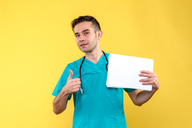 帅哥年轻男性医生的正视图 带着黄色地板上的健康病毒文件文件快乐微笑