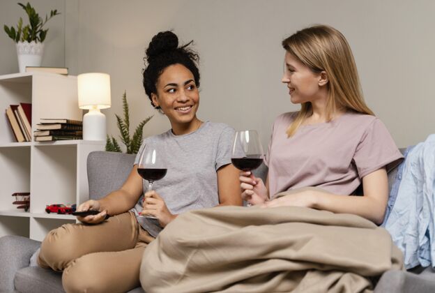 女人坐在沙发上看电视喝酒的女人电视遥控器房子休闲