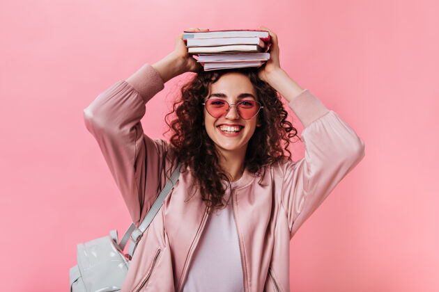 深色头发一个穿粉红色衣服的少女和书摆姿势女人模特笔记本