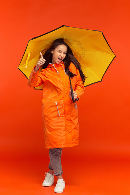 伞穿秋衣的年轻女孩在红色的衣服上摆姿势夹克时尚新潮