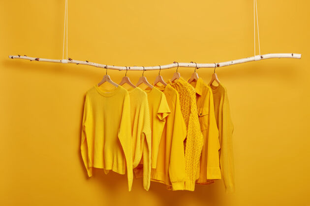 衣架专为女士设计的纯黄色毛衣和夹克系列 挂在更衣室的衣架上选择重点时尚的冬装或秋装木材精品明亮
