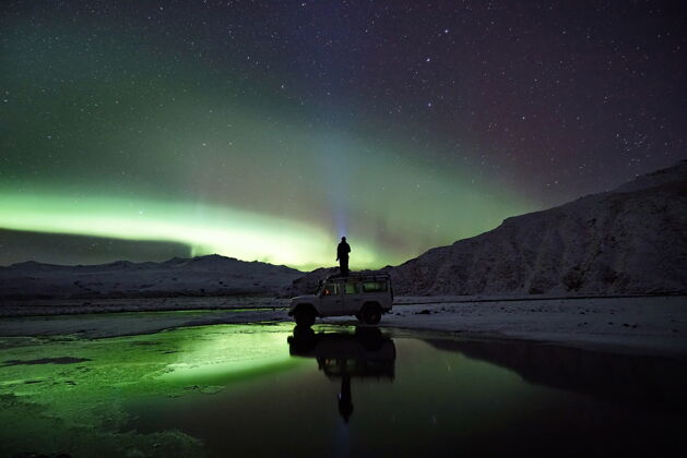 山脉站在越野车上看北极光的人冰岛极光户外