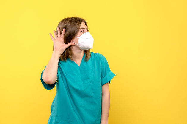 正面黄色地板医院医疗大流行上戴着口罩的年轻女医生的正面图人医院地板