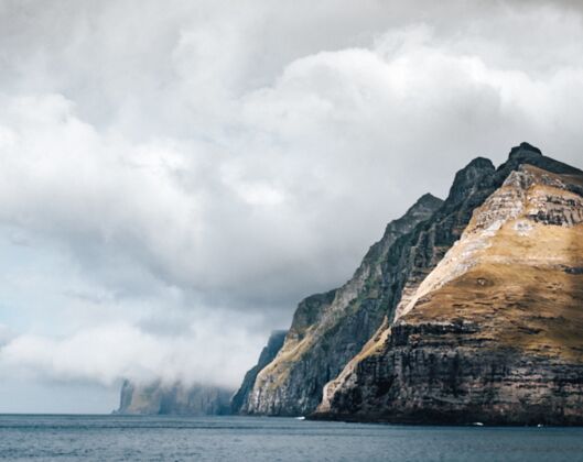 卡通巨大的悬崖被云层下的水包围着设计船海滩