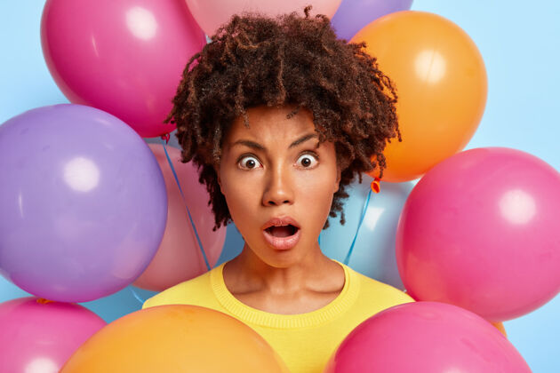 印象摄影棚的肖像 惊讶的年轻女子摆姿势周围的生日彩色气球生日惊人女人