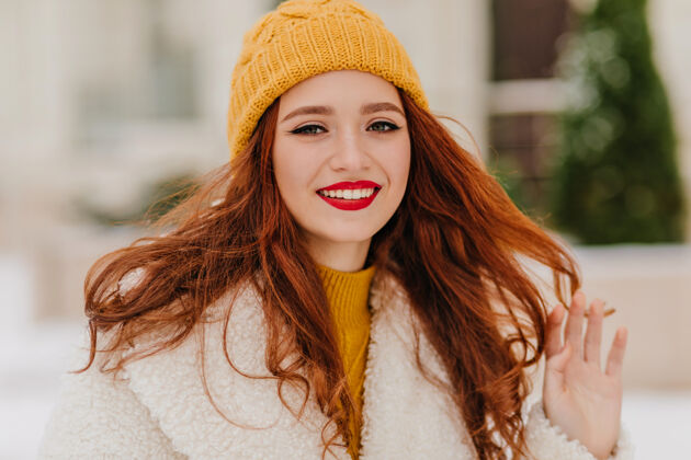 年轻戴着黄色可爱帽子的长发女孩在寒冷的日子里感到寒冷可爱的姜黄色年轻女子喜欢冬天的天气笑冬季脸