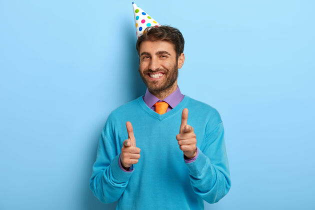 积极戴着生日帽 穿着蓝色毛衣的帅哥欢呼圆锥体领带