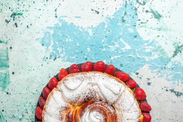 派顶视图糖粉蛋糕与新鲜的红色草莓淡蓝色的表面顶部新鲜饼干