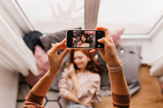 休闲拍照时手拿手机的照片姜姑娘在家给朋友摆姿势卷发女人年轻