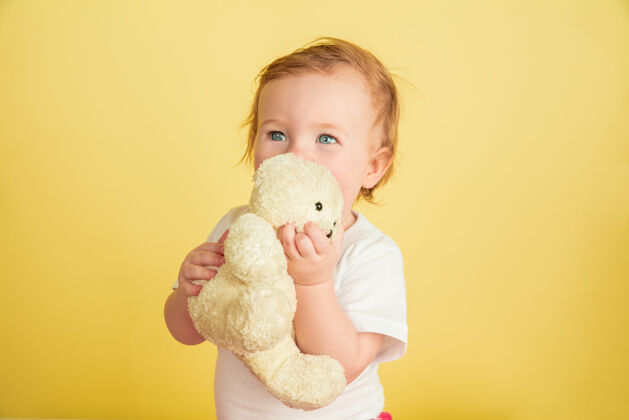 可爱白人小女孩 黄色工作室背景上孤立的孩子们可爱可爱的孩子的肖像 和泰迪熊玩耍的宝宝游戏明亮黄色