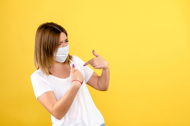 冠状病毒黄色墙壁上戴着无菌口罩的年轻女子的正视图面具正面大流行