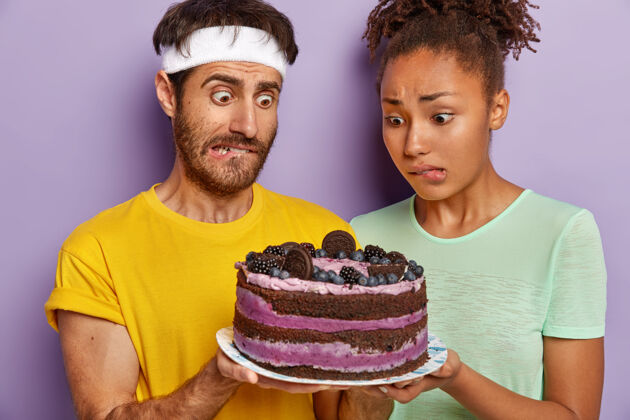 卷曲迷惑不解的活跃情侣摆着大蛋糕女人诱惑开胃菜