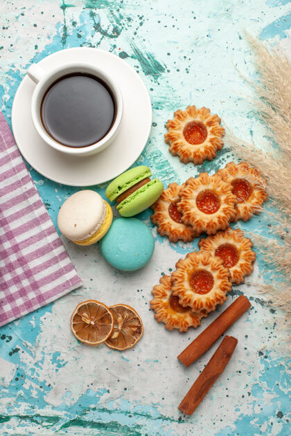 咖啡俯瞰法国马卡龙饼干和茶杯在蓝色的表面茶碟蛋糕餐