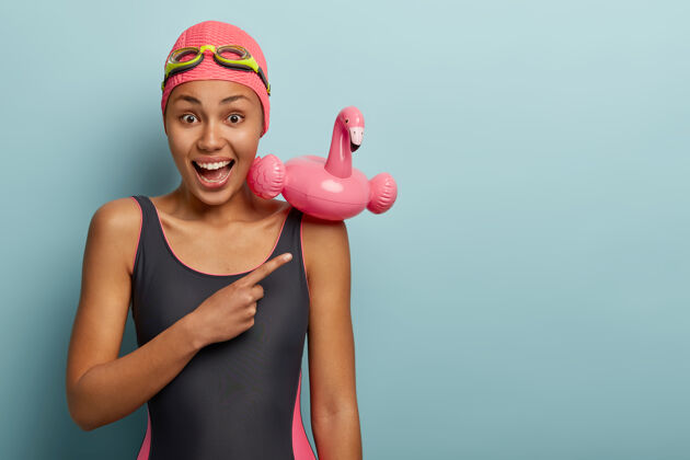 人情绪化的女游泳运动员戴着护目镜摆姿势游泳者泳装室内