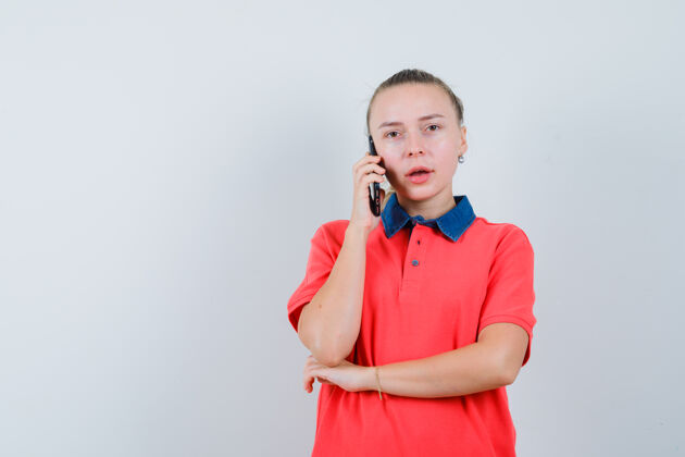 欢呼一位穿着t恤衫的年轻女士在讲手机 神情沉思手机快乐电话