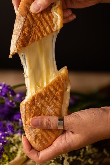 面包一个人的手拿着两块奶酪三明治的垂直镜头三明治快餐晚餐