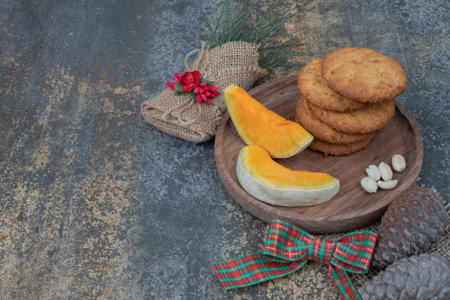 可食用饼干和南瓜片放在装饰着丝带的木板上高质量的照片曲奇南瓜甜点