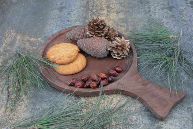 曲奇饼干 干玫瑰果和松果放在木板上高质量的照片小吃面包房树枝