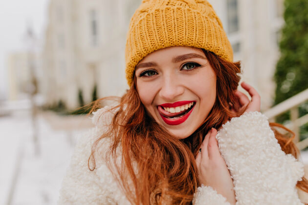 女人俏皮的姜女享受冬天的户外照片黄色帽子的可爱女士在户外散步女模特红发放松