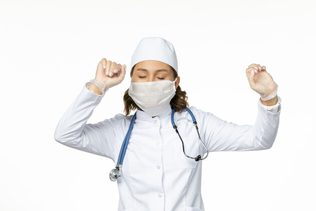女性正面图年轻女医生戴着无菌口罩和手套 由于冠状病毒在浅白的表面男性医生冠状病毒
