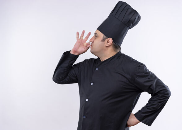 帽子男厨师身穿黑色制服 头戴厨师帽 站在白色背景上 展示美味的标志美味厨师烹饪