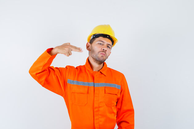 人穿制服的年轻工人用手和手指做手势 看上去很自信计算机头盔成人