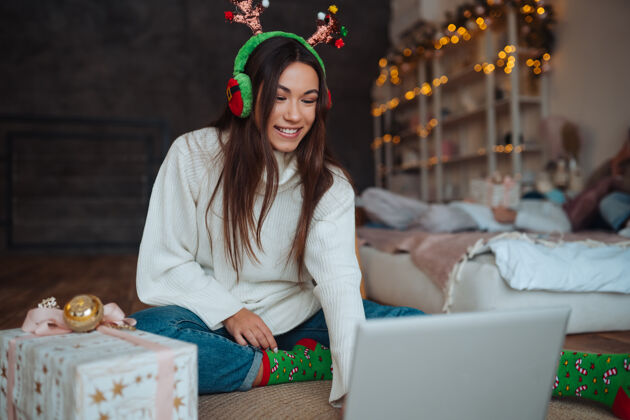 谈话在家里庆祝圣诞节期间 一只雌性的鹿角微笑着用笔记本电脑和网友聊天互联网季节在线