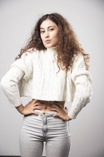 年轻穿着白色毛衣的年轻女子站在白色的墙上高质量的照片肖像女孩年轻